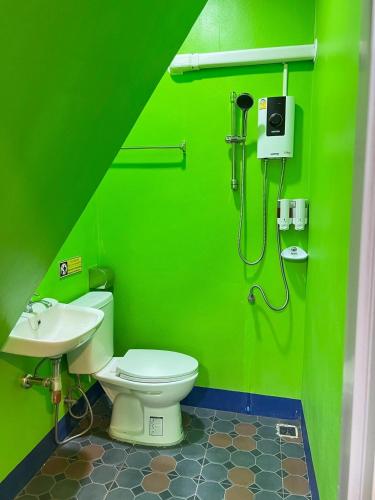 a green bathroom with a toilet and a sink at Baan Thammarot View in Sirindhorn