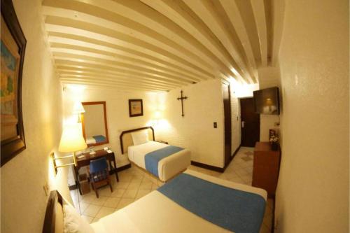 a bedroom with a bed and a cross on the wall at Hotel Del Portal, Puebla in Puebla