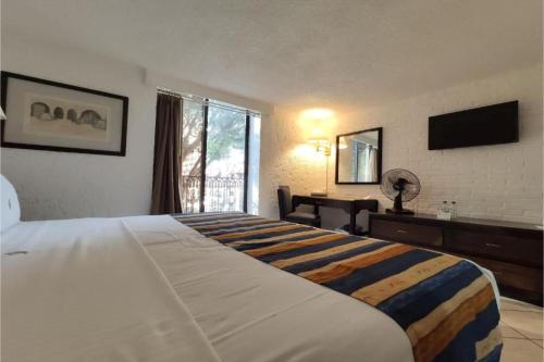 a hotel room with a large bed and a television at Hotel Del Portal, Puebla in Puebla