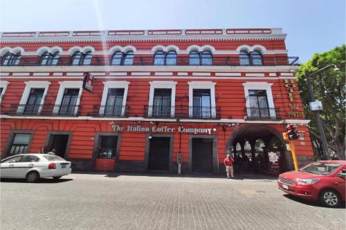 a red brick building with a man standing in front of it at Hotel Del Portal, Puebla in Puebla