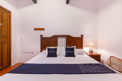 a bedroom with a large white bed with blue pillows at Capital O Posada La Casa De La Tia, Oaxaca in Oaxaca City