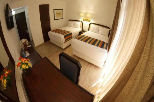 a hotel room with two beds and a desk at Hotel Del Portal, Puebla in Puebla