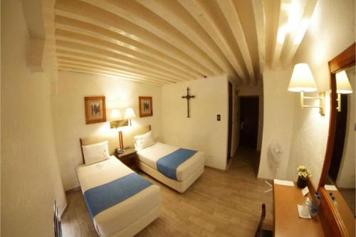 a hotel room with two beds and a cross on the wall at Hotel Del Portal, Puebla in Puebla
