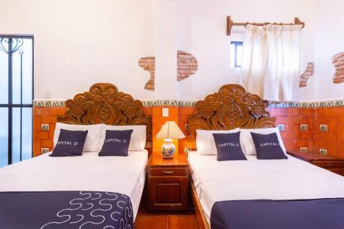 two beds in a room with two beds sidx sidx sidx at Capital O Posada La Casa De La Tia, Oaxaca in Oaxaca City