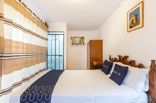 a bedroom with a large white bed with blue pillows at Capital O Posada La Casa De La Tia, Oaxaca in Oaxaca City