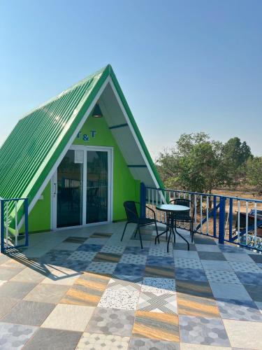 a green building with a table and chairs on a deck at Baan Thammarot View in Sirindhorn