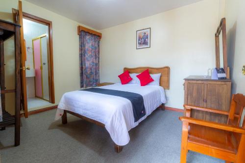a bedroom with a large bed with red pillows at Capital O Hospedaje Los Angeles San Cristobal De Las Casas in San Cristóbal de Las Casas