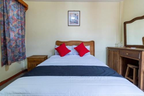 a bedroom with a bed with red pillows and a mirror at Capital O Hospedaje Los Angeles San Cristobal De Las Casas in San Cristóbal de Las Casas