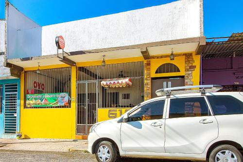 a white car parked in front of a yellow building at OYO Hotel Posada Los Faroles,Tabasco in Villahermosa