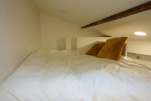 - une chambre avec un lit blanc et un oreiller jaune dans l'établissement Santé - LB - Petit cocon dans le 14ème, Paris pour 2p, à Paris