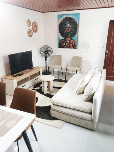 a living room with a white couch and a tv at T3 Moderne et Cosy, Riviera 3, 10min Abidjan mall in Abidjan