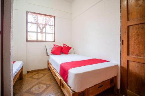 a bedroom with a bed with red pillows on it at OYO Cabañas Abril, Mazunte in Mazunte