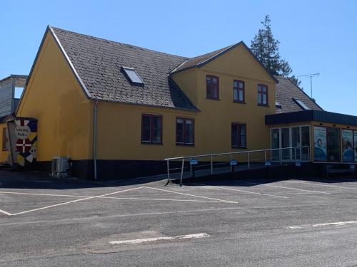 a yellow building with a parking lot in front of it at VikingBnB in Kirke Såby