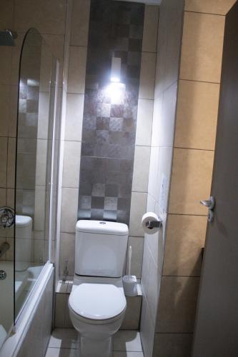 a small bathroom with a toilet and a bath tub at Ocean Breeze Hotel in Strand