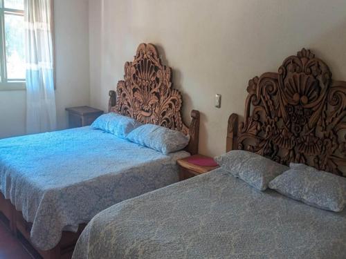 a bedroom with two beds and a large headboard at OYO Los Alcatraces in Tzintzuntzán