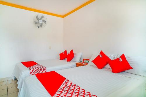 two beds in a room with red and white pillows at OYO Hospedaje Colibri in Chiapa de Corzo