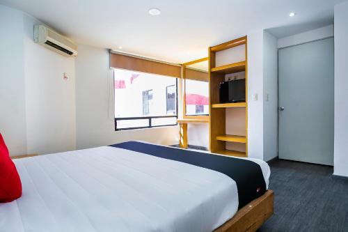 a bedroom with a large white bed and a window at Capital O Hotel Casa Blanca, Morelia in Morelia