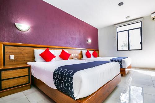 a bedroom with two beds with red and blue pillows at Capital O Hotel Casa Blanca, Morelia in Morelia