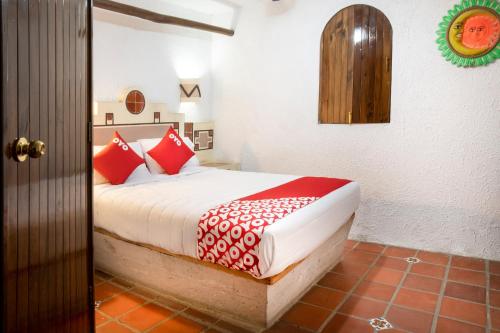 a bedroom with a bed with red and white pillows at OYO Posada Astrud,Cuetzalan in Cuetzalán del Progreso