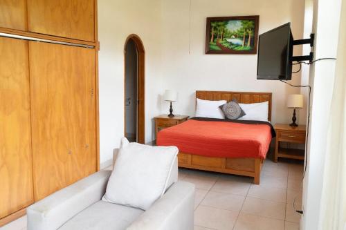 a bedroom with a bed and a couch and a tv at Capital O La Joya Del Lago in Ajijic