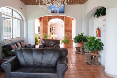 a living room with leather couches and a chandelier at Capital O La Joya Del Lago in Ajijic