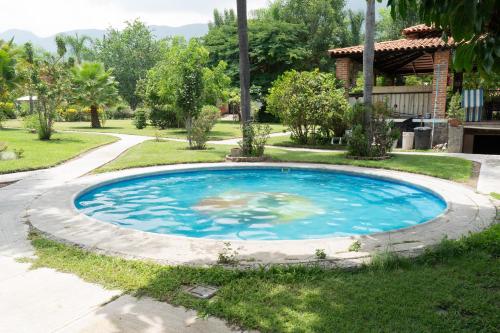 a large blue pool in the grass next to a house at Capital O La Joya Del Lago in Ajijic