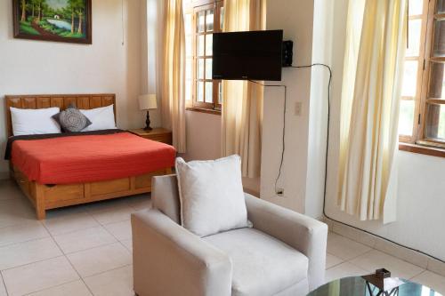 a bedroom with a bed and a chair and a tv at Capital O La Joya Del Lago in Ajijic