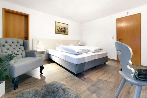 a bedroom with a bed and a chair at Hotel ChiemseePanorama in Gstadt am Chiemsee