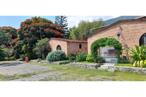 a brick building with an arch and a garden at Capital O Posada Del Pescador Jocotepec in Chapala