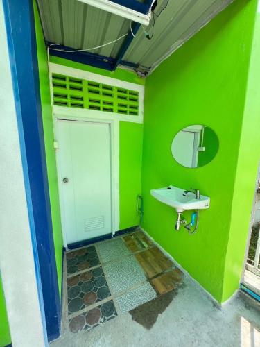 a green bathroom with a sink and a mirror at Baan Thammarot View in Sirindhorn