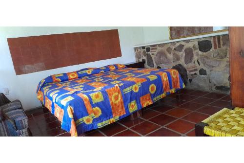 a bedroom with a bed with a colorful blanket at Capital O Posada Del Pescador Jocotepec in Chapala
