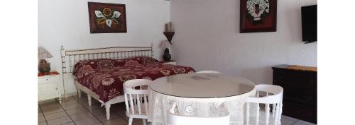 a bedroom with a bed and a table and chairs at Capital O Posada Del Pescador Jocotepec in Chapala