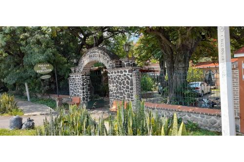 a stone archway in a park with a tree at Capital O Posada Del Pescador Jocotepec in Chapala
