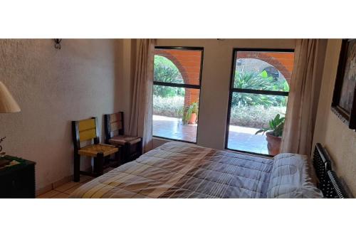 a bedroom with a bed and a large window at Capital O Posada Del Pescador Jocotepec in Chapala