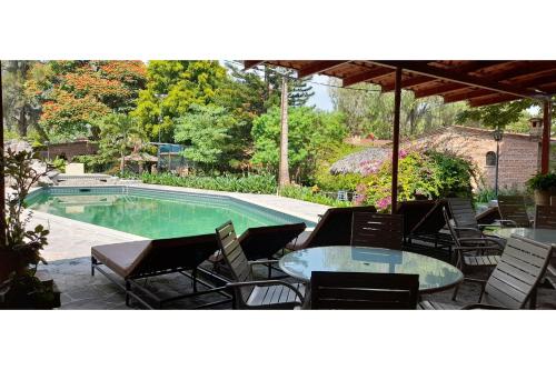 a pool with chairs and a table and an umbrella at Capital O Posada Del Pescador Jocotepec in Chapala