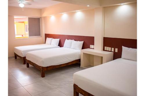 a hotel room with two beds and a table at OYO Hotel La Playa in Zihuatanejo