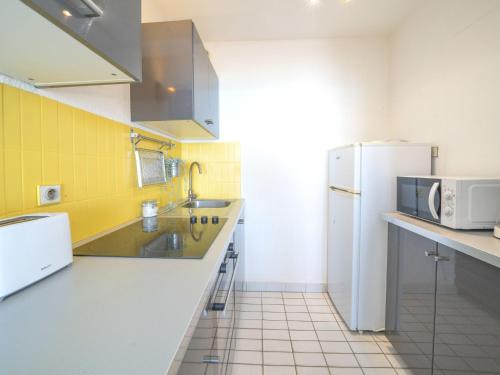 - une cuisine avec des murs jaunes et un réfrigérateur blanc dans l'établissement Apartment Poséidon by Interhome, à La Grande Motte