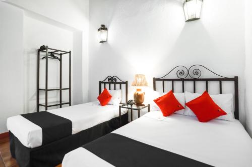 two beds in a room with red and black pillows at Capital O El Nito Posada in Oaxaca City