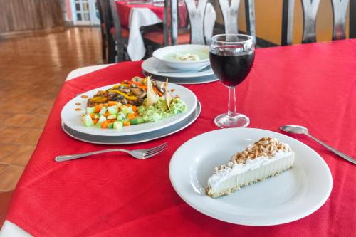 a table with two plates of food and a glass of wine at OYO Hotel Casa Blanca in Martínez de La Torre