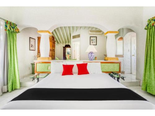 a bedroom with a large white bed with red pillows at Capital O Gran Hotel Campestre in Celaya