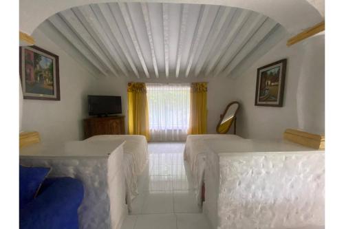 a white room with two beds and a window at Capital O Gran Hotel Campestre in Celaya
