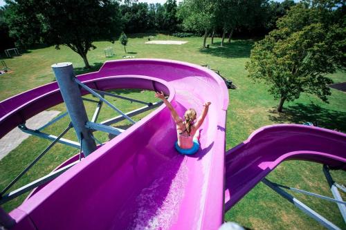 a girl is sliding down a purple water slide at Knus chalet in het hart van Zeeland - VP028 in Heinkensand