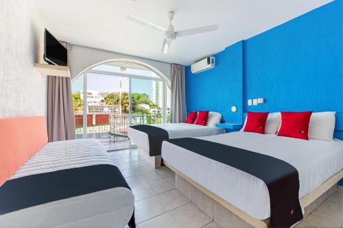 two beds in a room with blue and red walls at Capital O Hotel El Mejicano, Acapulco in Acapulco