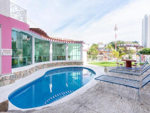 a villa with a swimming pool and a house at Capital O Hotel El Mejicano, Acapulco in Acapulco