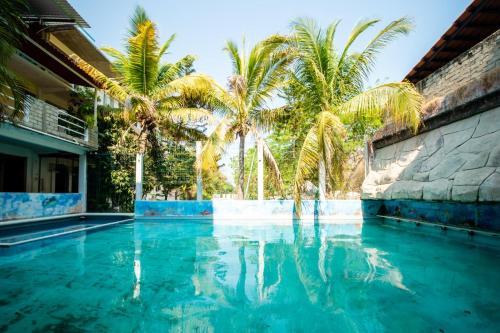 a swimming pool with palm trees in front of a house at OYO Hotel Betsua Vista Hermosa, Huatulco in Santa Cruz Huatulco