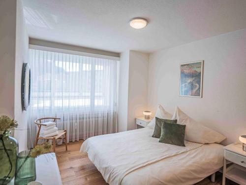 a bedroom with a white bed and a window at Apartment Chesa Fleury by Interhome in St. Moritz