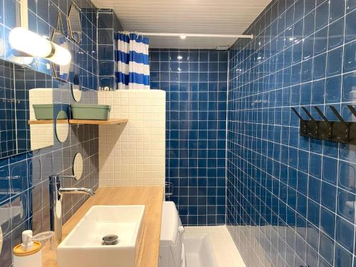 La salle de bains est pourvue de carrelage bleu, d'un lavabo et de toilettes. dans l'établissement Appartement à Perros-Guirec proche plage avec balcon et vue mer - FR-1-368-416, à Perros-Guirec