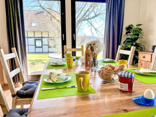 a wooden table with green napkins and food on it at Holiday Home Hänsel & Gretel im Kellerwald by Interhome in Frankenau