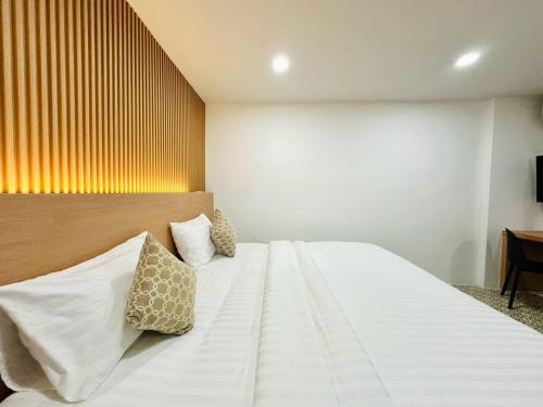 a bedroom with a large white bed with pillows at The Cozy 77 in Bangkok