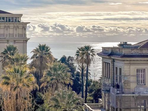 Elle offre une vue sur un bâtiment, des palmiers et l'océan. dans l'établissement Apartment Le Mirazur by Interhome, à Nice